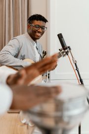 a-man-wearing-glasses-is-energetically-playing-a-drum-focused-on-his-rhythm